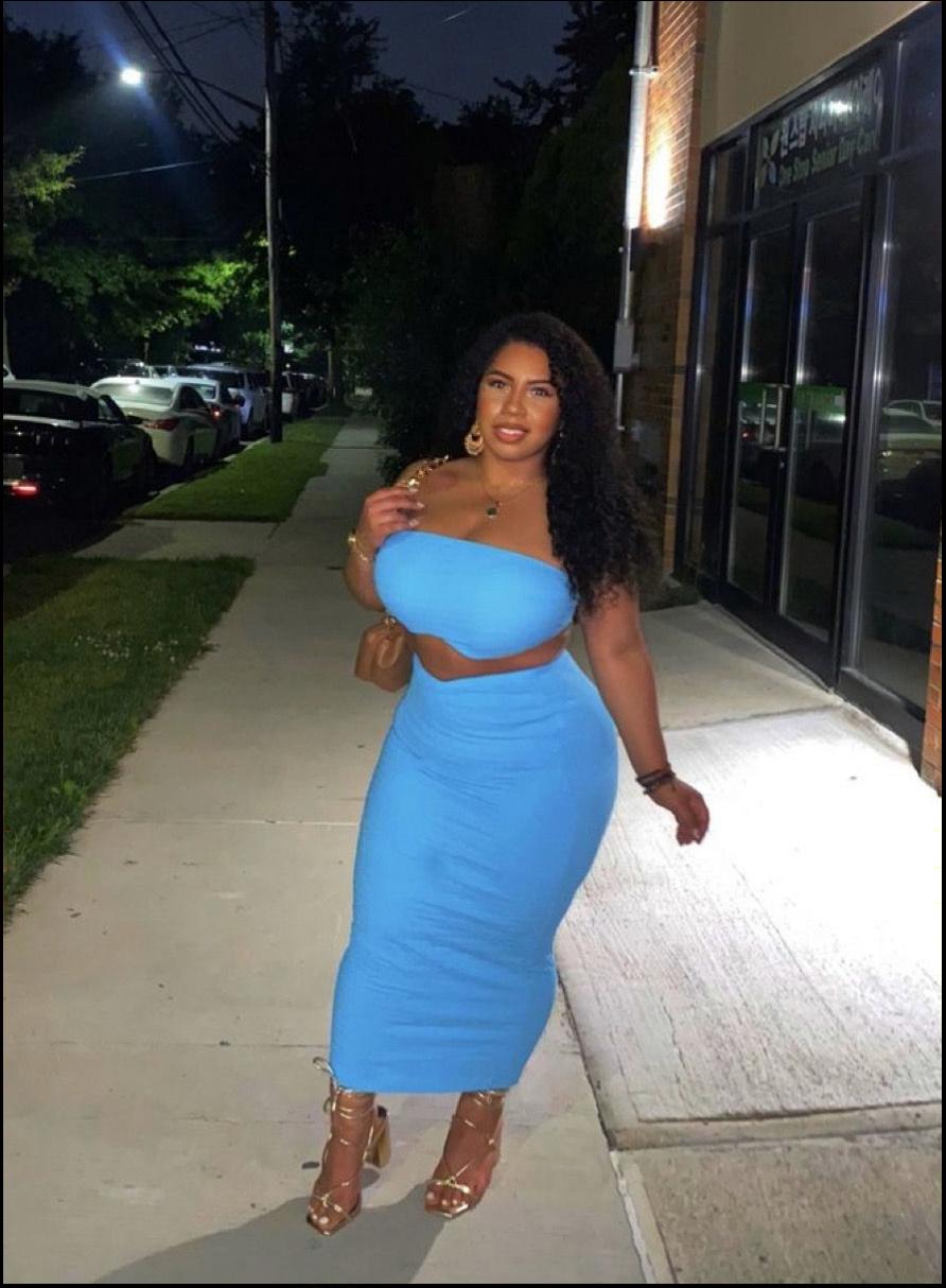 a woman in a red dress standing on a sidewalk