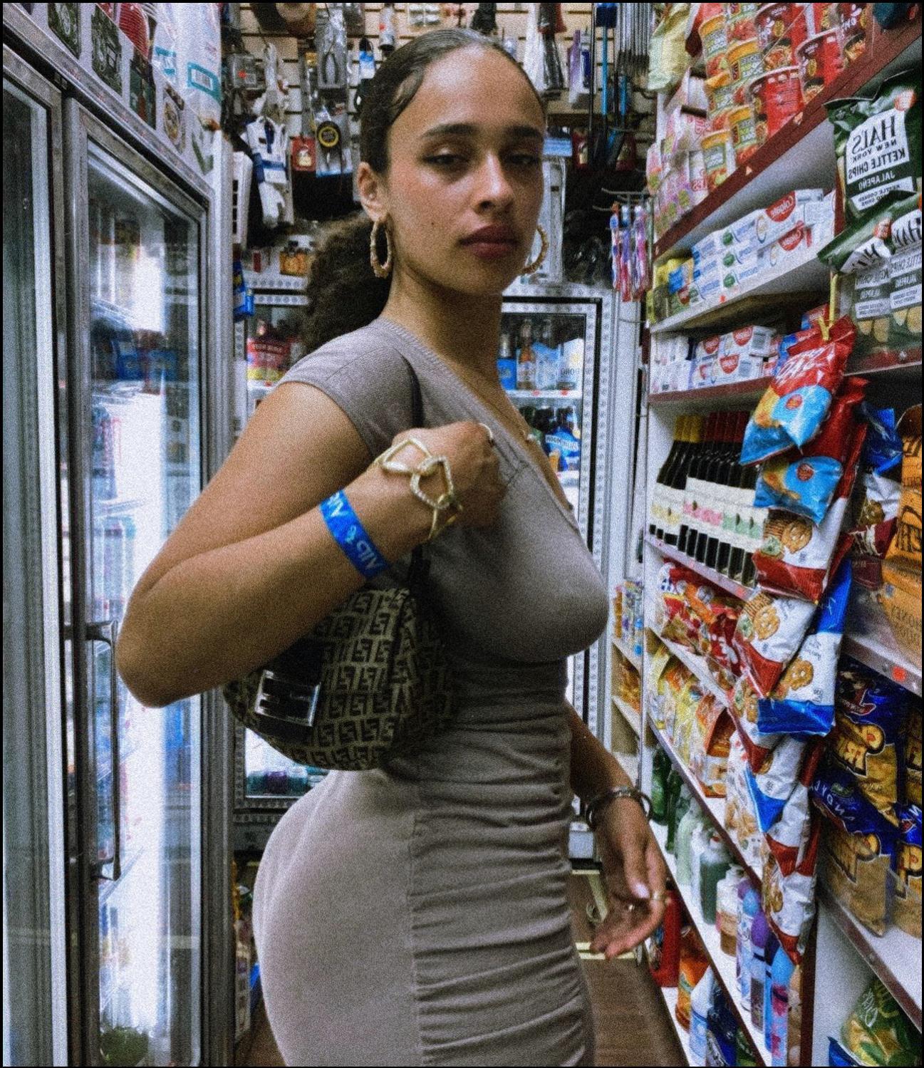 a woman in a black t-shirt is standing in front of a store