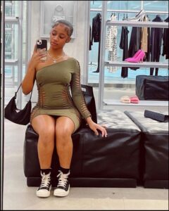 a woman in a black dress is sitting on a couch