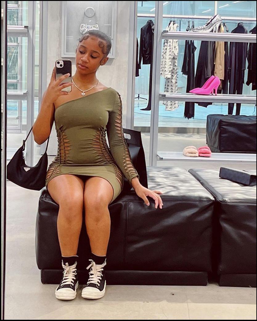 a woman in a black dress is sitting on a couch