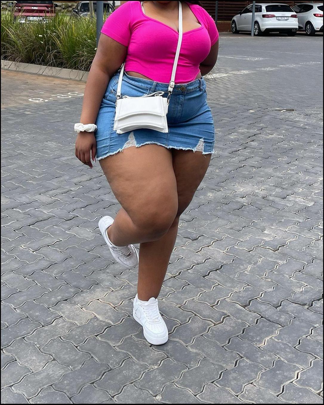 a woman in a pink dress is walking on a sidewalk