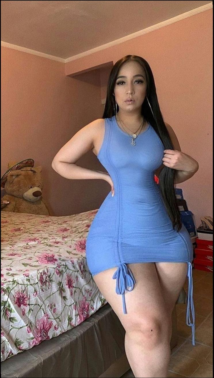 a woman in a red dress is standing on a bed