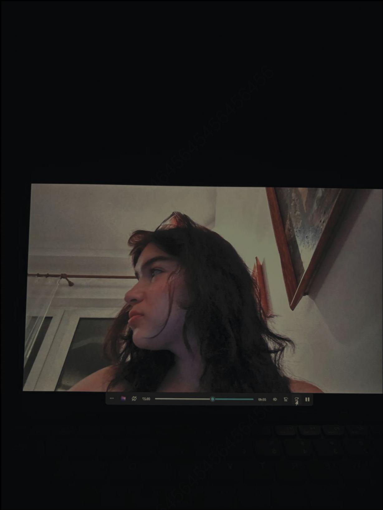 A video player displays a profile view of a person with long dark hair, looking to the right. The video is playing on a laptop screen with a dark background. The video player shows a timestamp of 06:50.