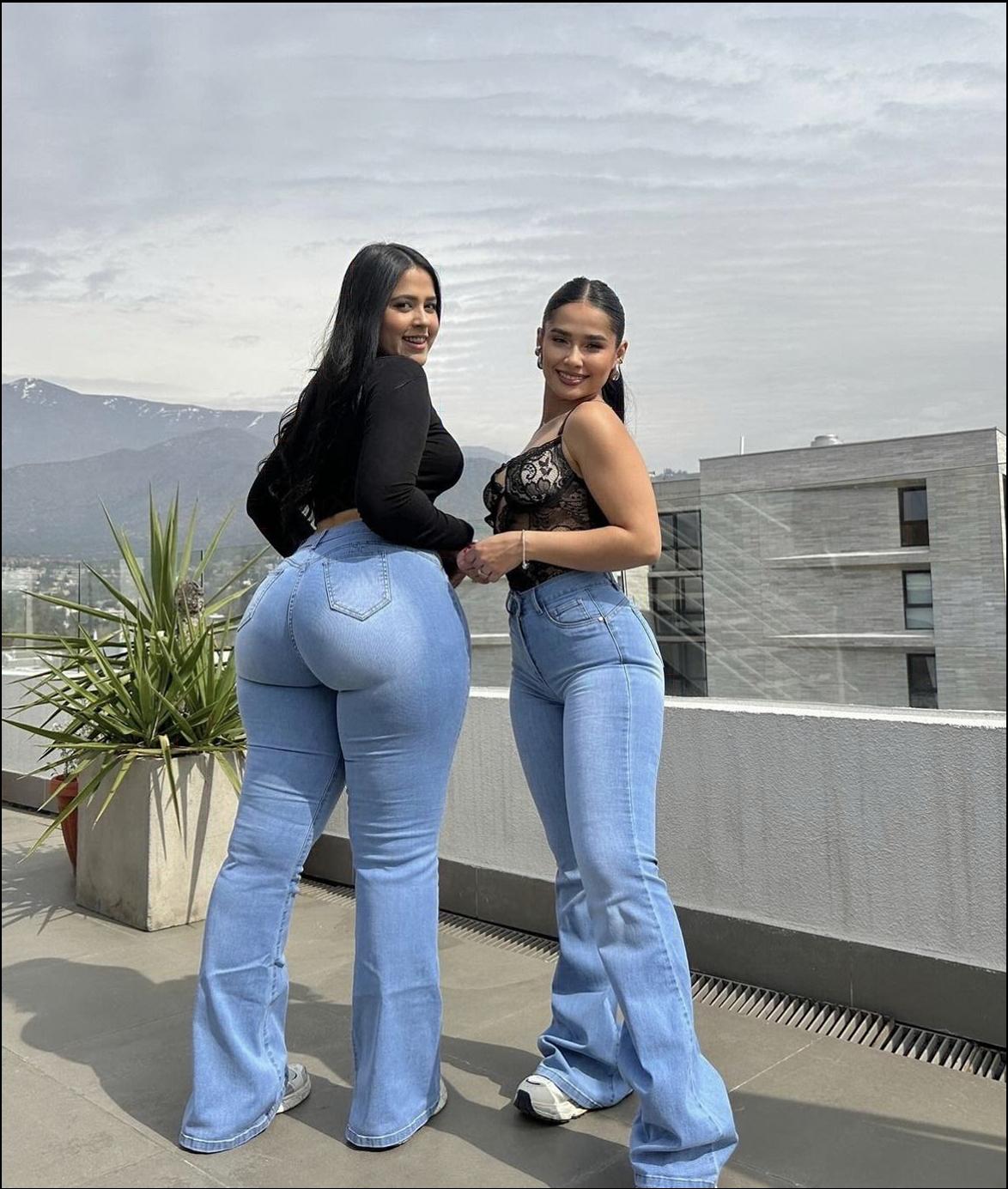 two women are standing on a sidewalk near a building