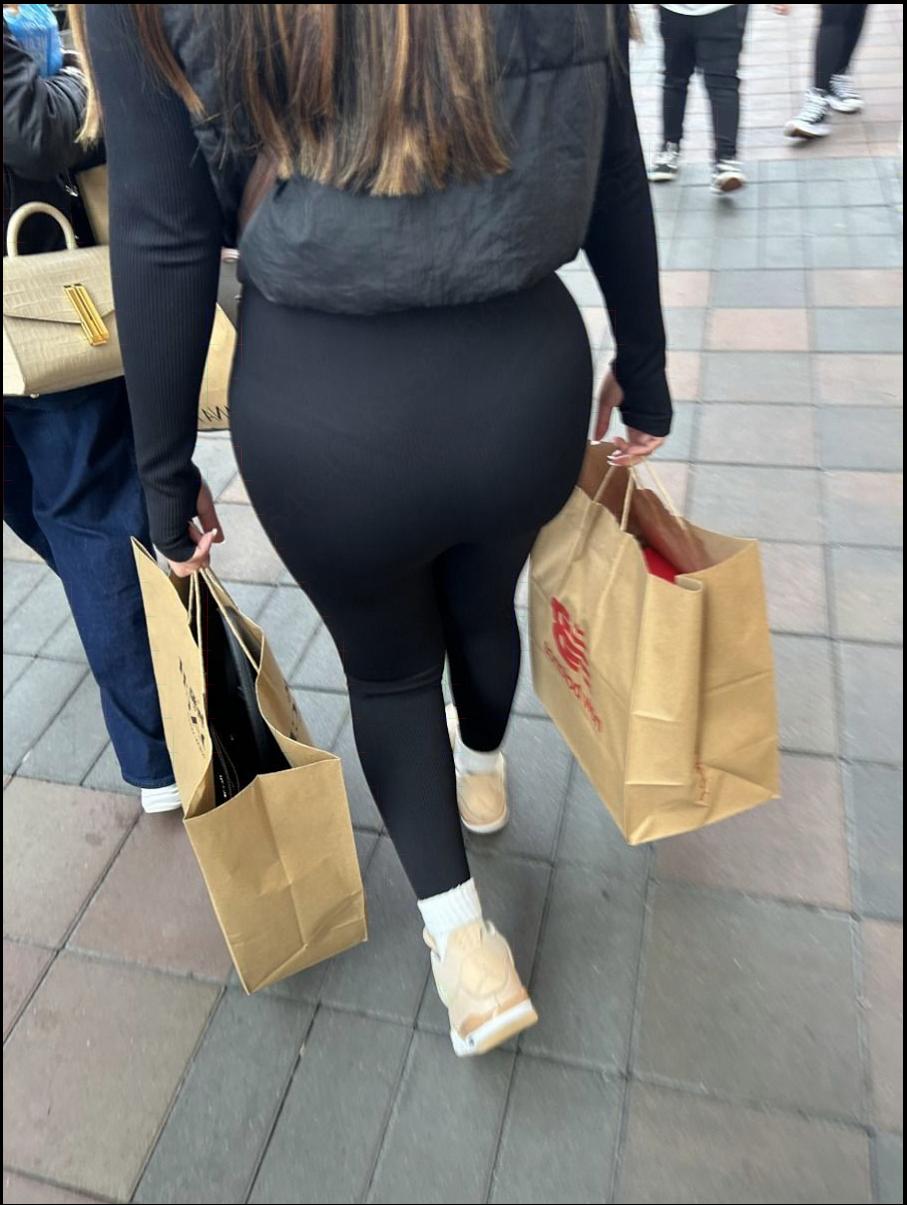 a woman walking down a sidewalk with a bag
