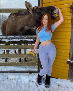 a woman standing in front of a fence with a cow