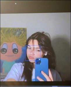 a woman holding a cell phone in front of a picture