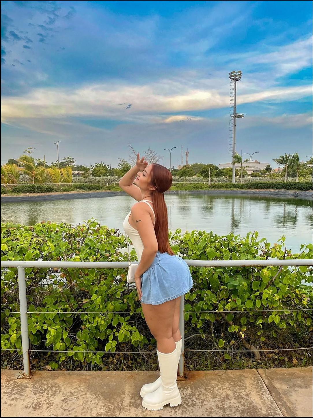 a woman is standing on a ledge near a fence