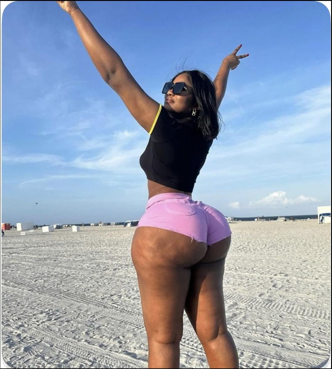 a woman is standing on a beach with a frisbee