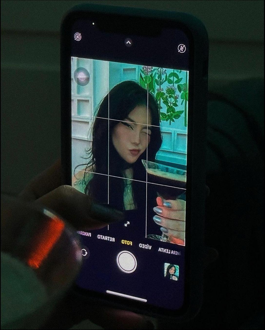 a woman holding a cell phone in front of a tv