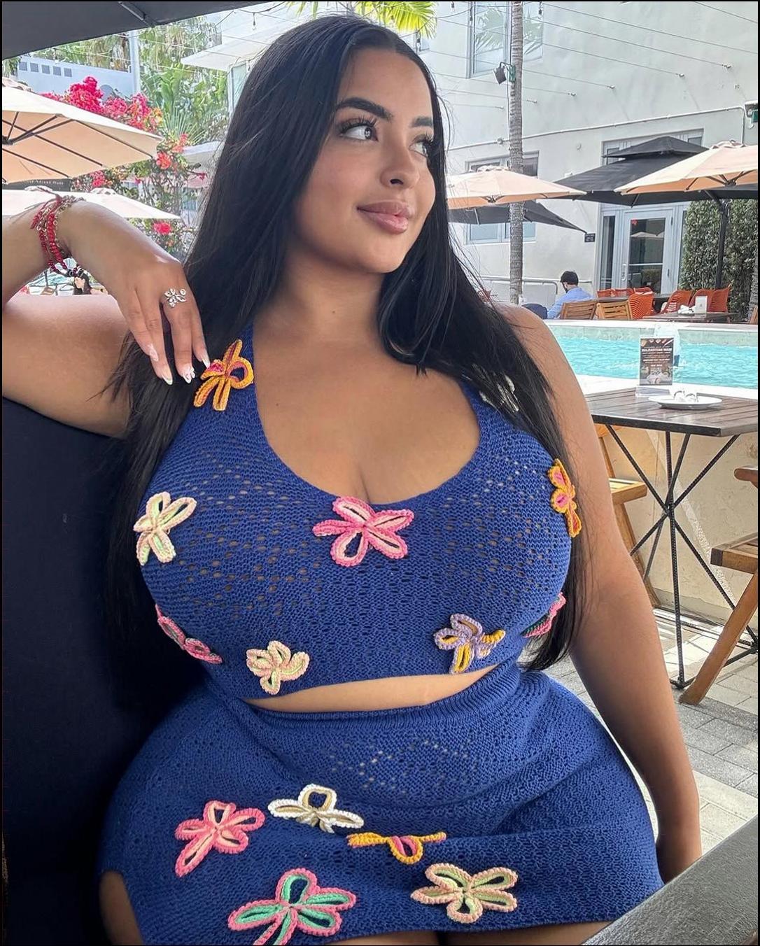 a woman is sitting on a bench with a blue umbrella