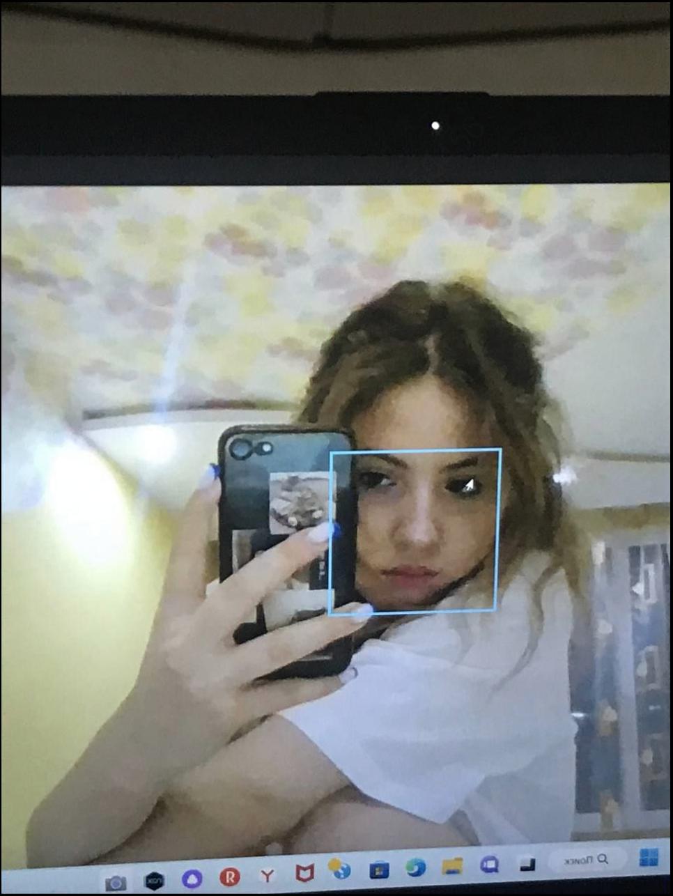 a woman holding a cell phone in front of a picture of a man