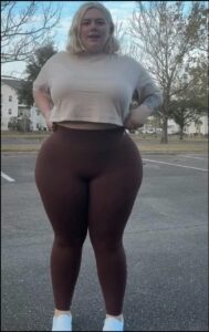 a woman is standing on a sidewalk with a black and white t-shirt